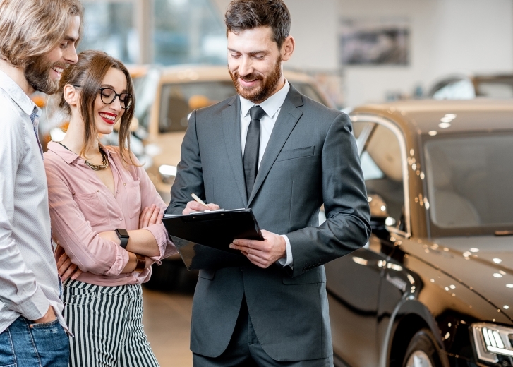 salesman at car dealership with customers